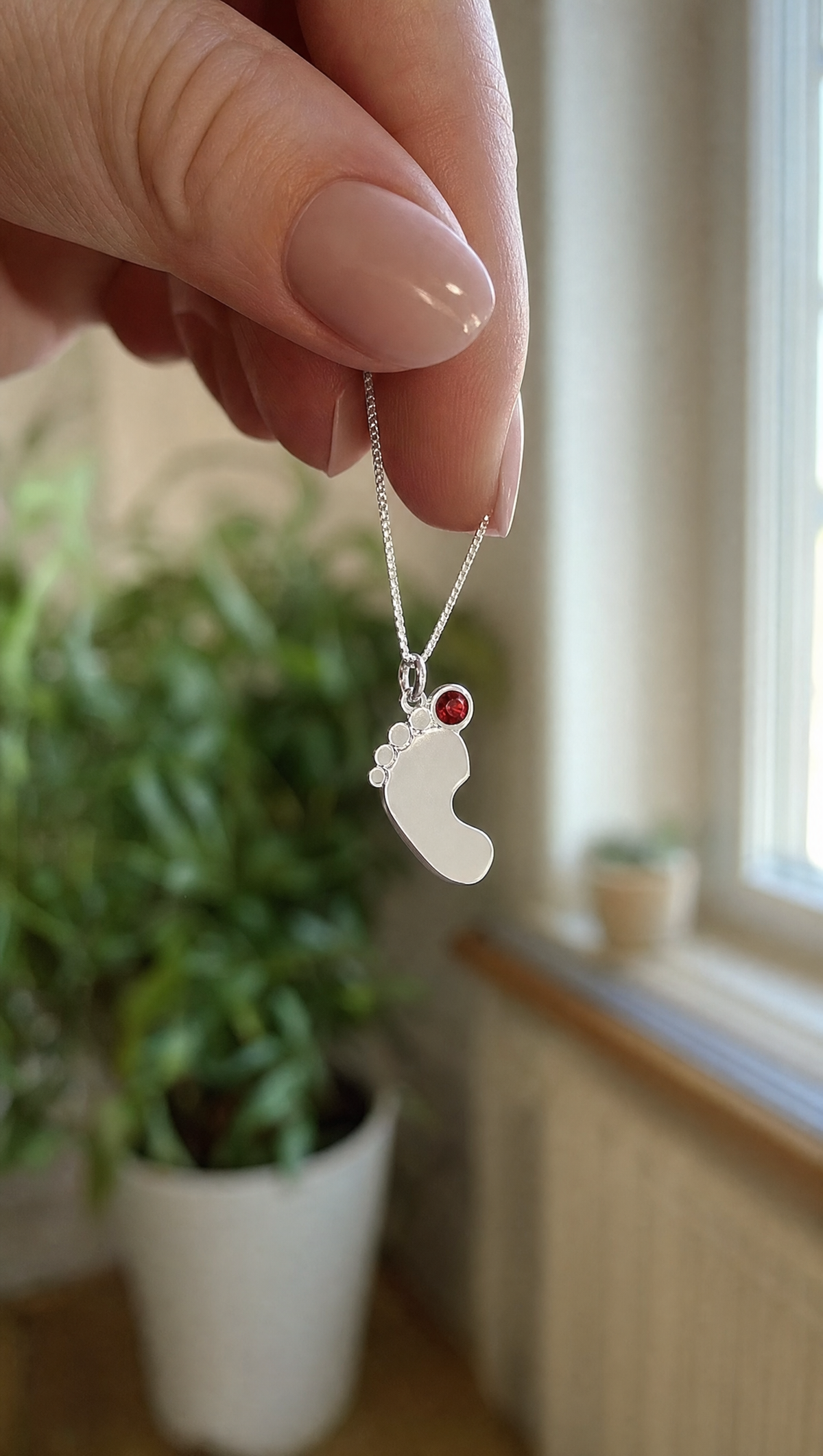 Baby feet birthstone necklace held up in natural light
