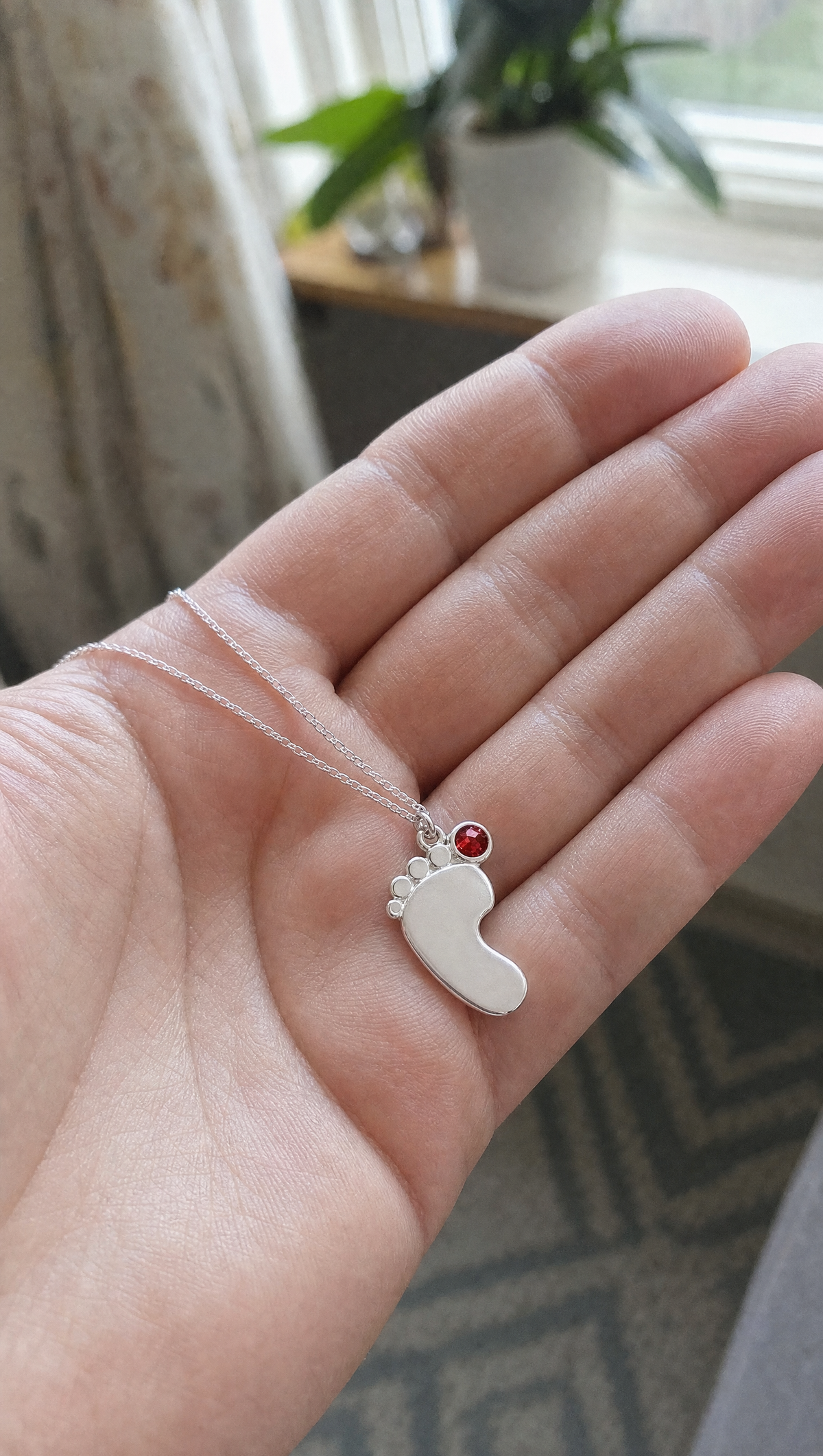 The baby feet charm resting in an open palm