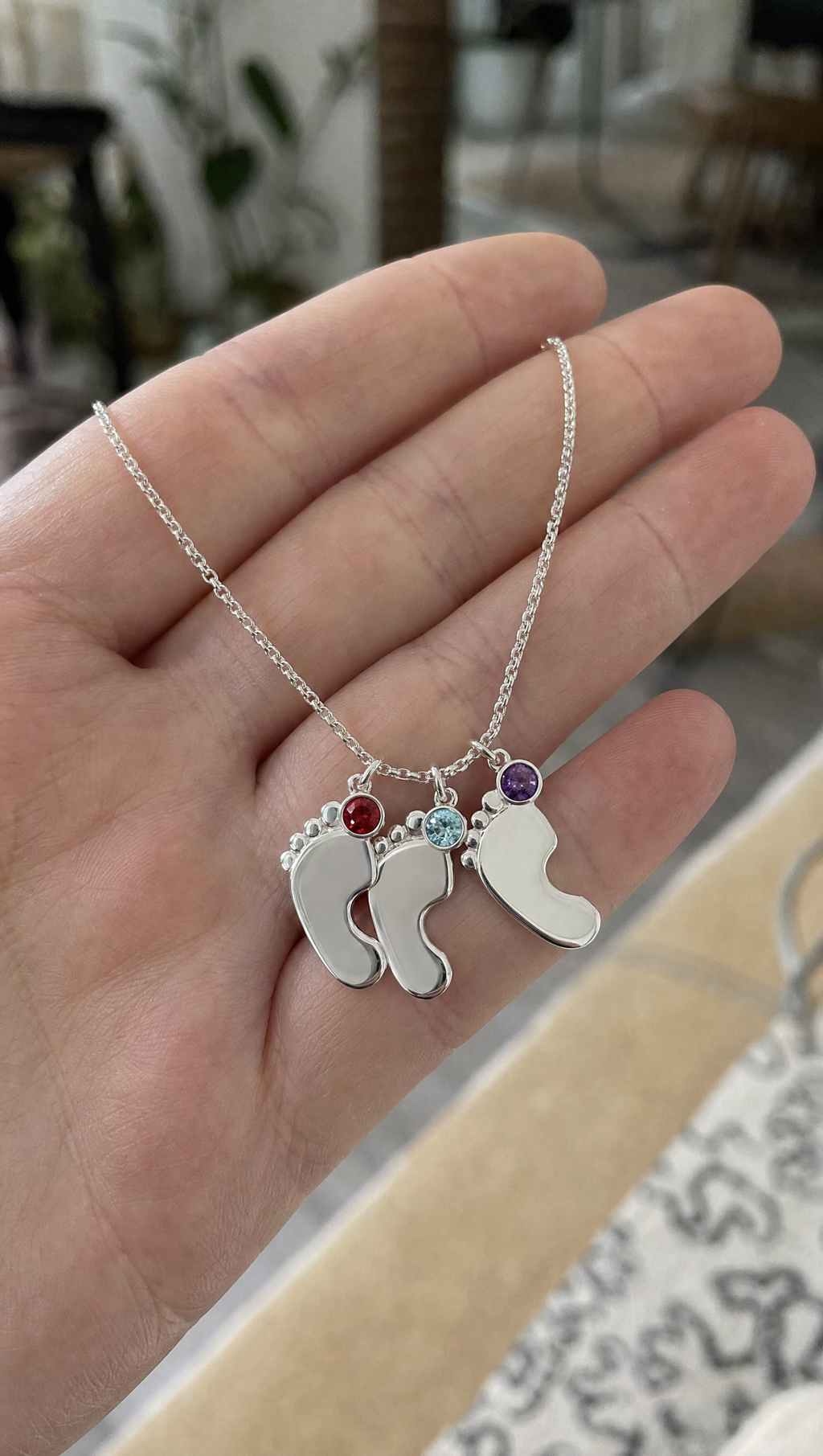 Three baby feet charms, each with its own birthstone